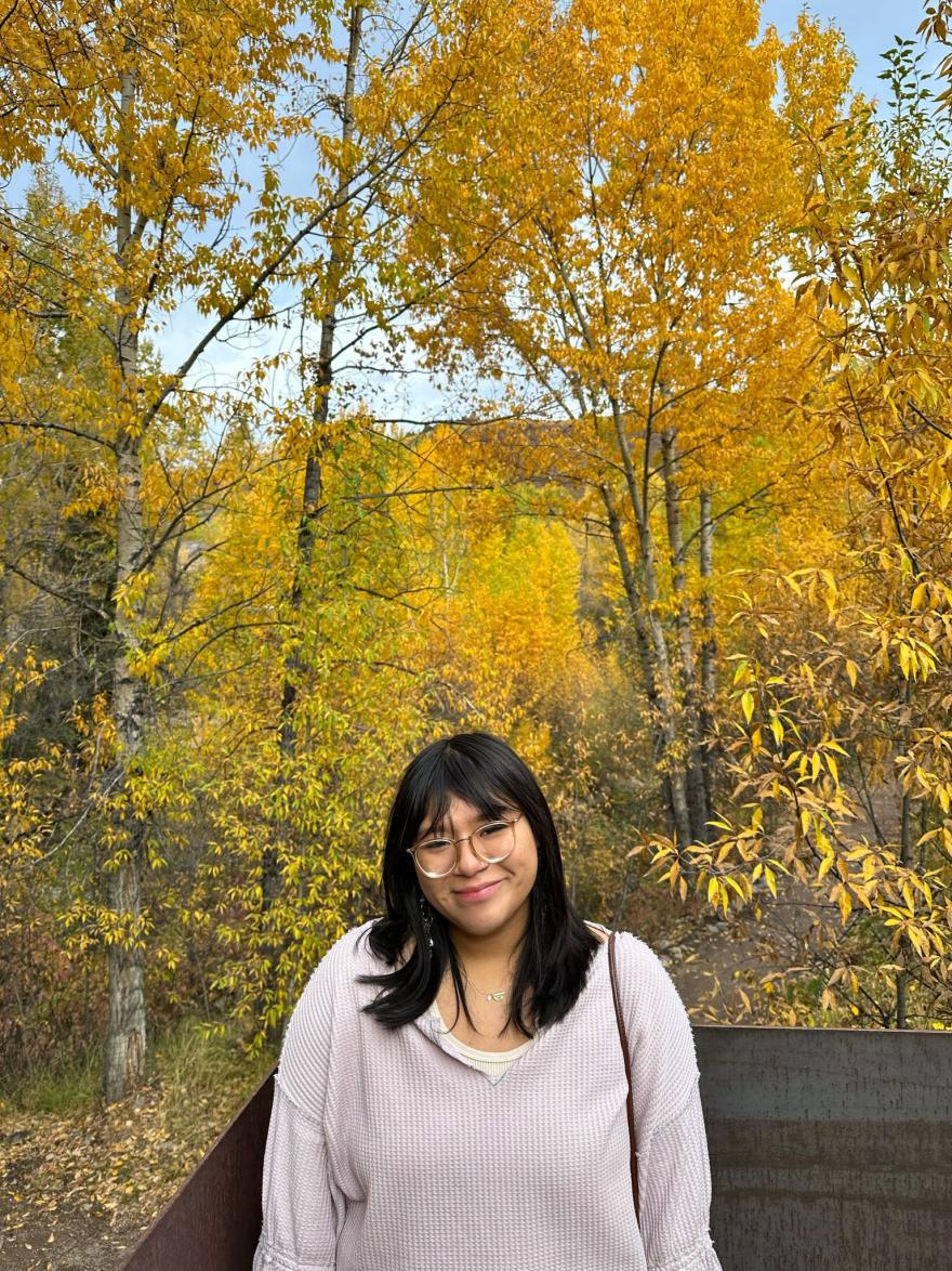 Andrea Torres posing for picture with golden Aspen groves as a backdrop. 
