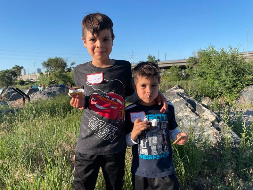 Two brothers eating s'mores outside. 