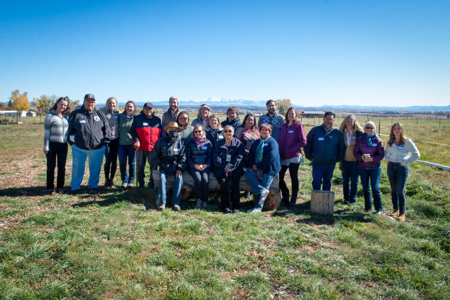 Attendees of "Regina's Event" pose on a field of grass in front of a bold mesa. Photo by Sarah Schwab